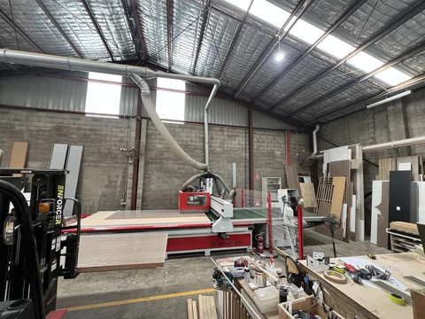 Wide view of the machine area, extraction ducting, sheet storage and surrounding workshop items.