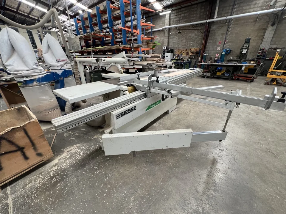 Workshop machine with extended sliding supports, extraction hoses and stock racking behind it.