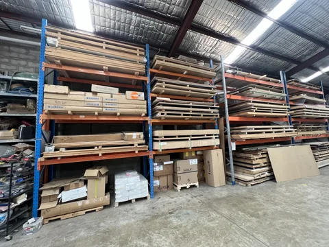 Blue and orange racking holding long materials, with sheet stock and other items stored below.