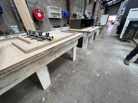 Long workbenches with hand tools, loose components and equipment in the workshop.