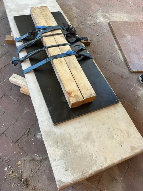 Timber reinforcement, protective panels and ratchet straps arranged across a sandstone top before handling.