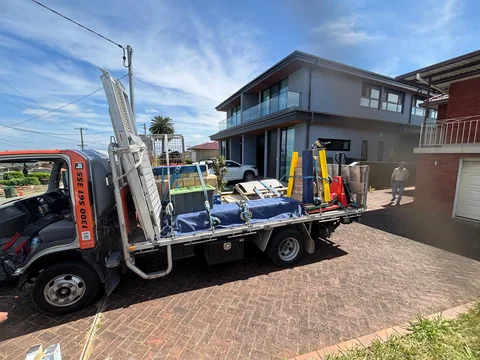 Truck at the residential property with supported stone sections and moving equipment on its tray.