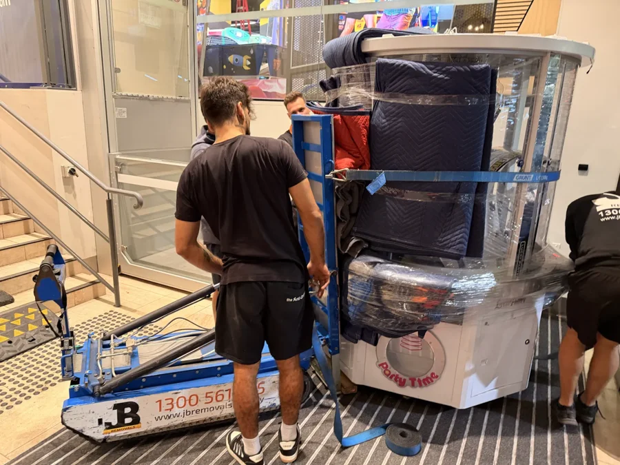 JB Removals crew controlling a protected glass arcade machine on stairs