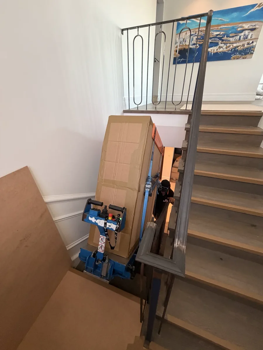 A custom-wrapped 250kg marble coffee table secured to JB stair-climbing equipment in a narrow Bondi Beach staircase